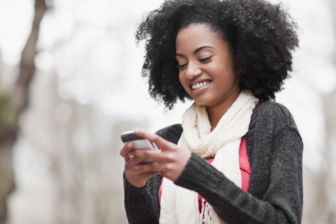 USA, Washington State, Seattle, Cheerful young woman text messaging. Photo : Take A Pix Media