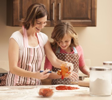 Mother and daughter (10-11) preparing pizza in kitchen. Photo : Mike Kemp