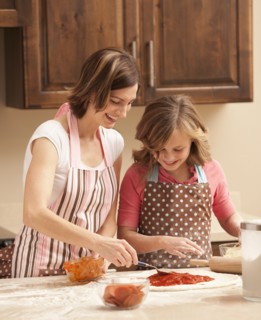Mother and daughter (10-11) preparing pizza in kitchen. Photo : Mike Kemp