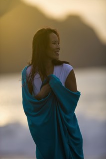 USA, California, San Francisco, Young woman wrapped in blanket at coast. Photo : Noah Clayton