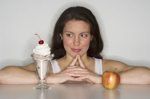 Woman choosing between ice cream and apple.