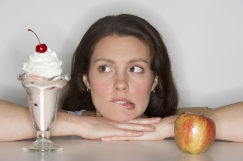 Woman choosing between ice cream and apple.