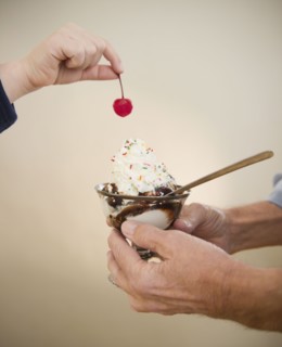Close up of hands of grandfather and grandson (8-9) holding icecreame and cherry. Photo : Jamie