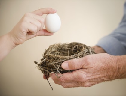 Close up of hands of grandfather and grandson (8-9) holding bird's nest and egg. Photo : Jamie