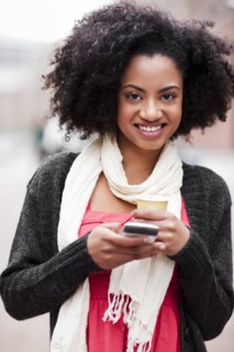 USA, Washington State, Seattle, Cheerful young woman text messaging while holding takeaway coffee.