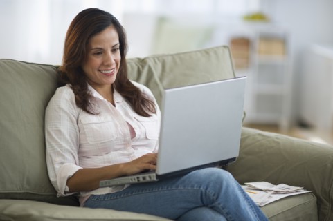 Woman sitting on sofa and using laptop.