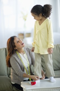 Mother preparing daughter's (6-7) clothing.