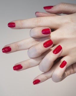 Close up of woman's clasped hands with red nail polish.