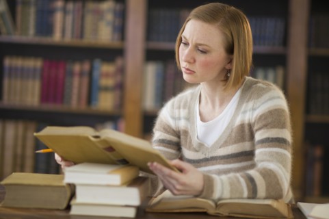 Woman reading book in library.