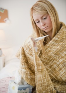 Woman wrapped in blanket measuring temperature. Photo: Jamie Grill Photography