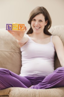 Young pregnant woman holding plastic letters reading: 'boy'. Photo : Mike Kemp