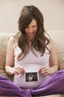 Young pregnant woman looking at CT image of unborn baby. Photo : Mike Kemp