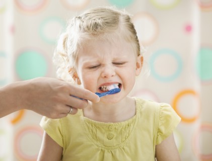 Girl (2-3) having teeth brushed. Photo : Mike Kemp