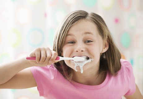 Girl (10-11) brushing teeth in messy way. Photo : Mike Kemp