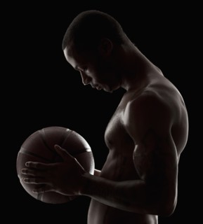 Studio shot of shirtless man holding basketball. Photo : Mike Kemp