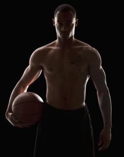 Studio portrait of shirtless man holding basketball. Photo : Mike Kemp