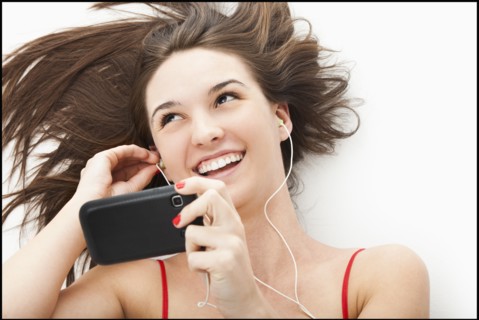 Young woman listening to mp3 player. Photo : Mike Kemp