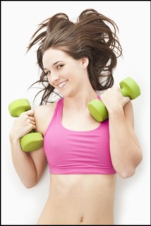Studio portrait of young woman holding hand weights. Photo: Mike Kemp