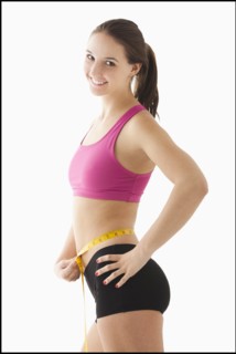 Studio portrait of young woman measuring waist. Photo : Mike Kemp