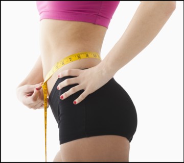 Young woman measuring waist. Photo : Mike Kemp