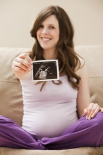 Young pregnant woman showing CT image of unborn baby. Photo : Mike Kemp