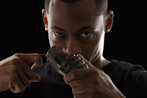 Studio portrait of young man holding grenade. Photo : Mike Kemp
