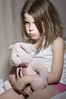 Studio portrait of sad girl (6-7) with pink teddy bear. Photo: Justin Paget