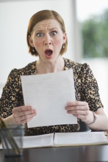 Woman reading document looking surprised.