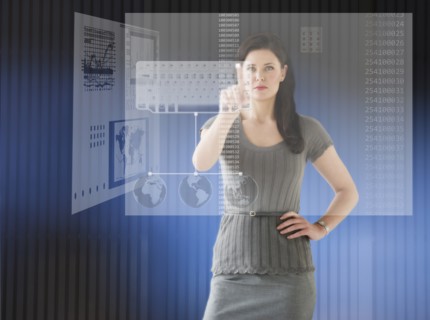 Woman in futuristic office touching computer panel.