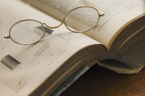 Close up of antique glasses lying on open book.