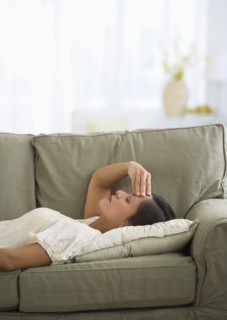 Woman lying on sofa with headache.