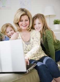 Mother and daughters (8-11) using laptop. Photo : Jamie Grill Photography