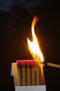 Close up of matches with one burning.