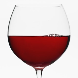 Close up of glass of red wine on white background.
