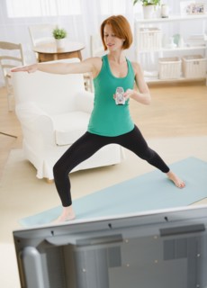 Woman watching tv and exercising. Photo : Jamie Grill Photography