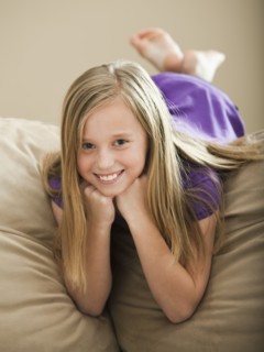 Portrait of girl (8-9) lying on sofa. Photo : Mike Kemp