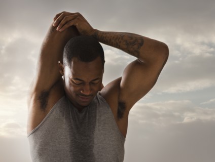 Young man exercising, cloudy sky in background. Photo : Mike Kemp