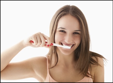 Studio portrait of young woman brushing teeth. Photo : Mike Kemp
