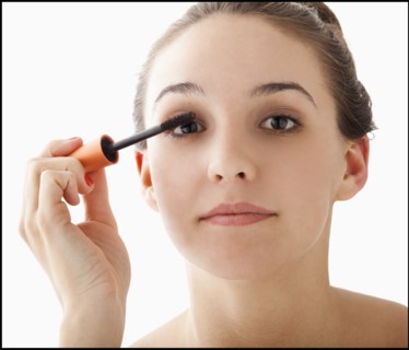 Studio portrait of young woman applying mascara. Photo: Mike Kemp