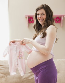 Young pregnant woman showing baby clothes. Photo: Mike Kemp