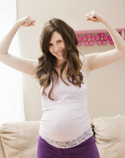 Young pregnant woman flexing muscles. Photo : Mike Kemp