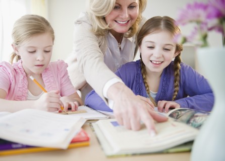 Mother helping daughters (8-11) with homework. Photo : Jamie Grill Photography