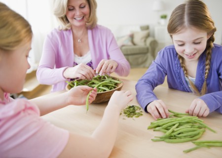 Mother and daughters (8-11) husking vegetables. Photo: Jamie Grill Photography