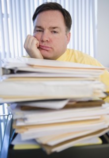 Businessman behind stack of paperwork. Photo : Jamie Grill Photography