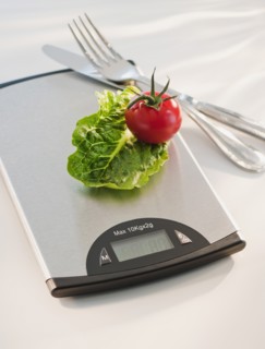 Lettuce and tomato on weight scale.