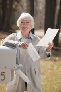 USA, Virginia, Richmond, senior woman reading letters by mailbox. Photo: Mark Edward Atkinson