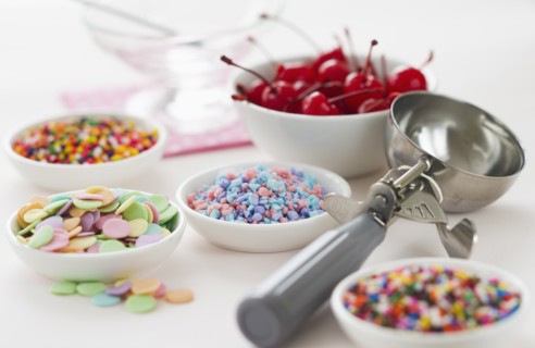 Close up of scoop and bowls with colorful toppings for ice creams.