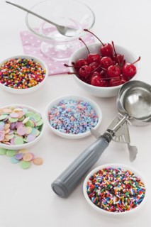 Close up of scoop and bowls with colorful toppings for ice creams.