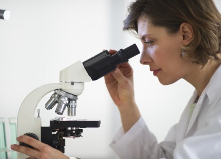 Woman in laboratory looking through microscope.