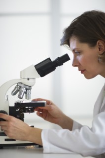 Woman in laboratory looking through microscope.